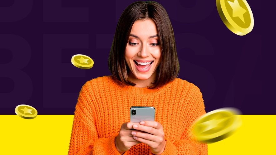 Imagem mostra mulher sorrindo ao utilizar um celular enquanto moedas caem