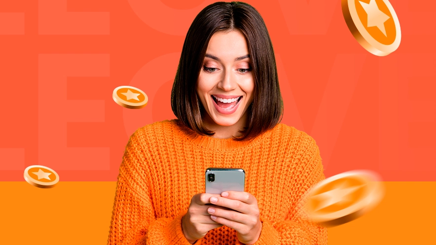 Imagem mostra mulher sorrindo ao utilizar um celular enquanto moedas caem