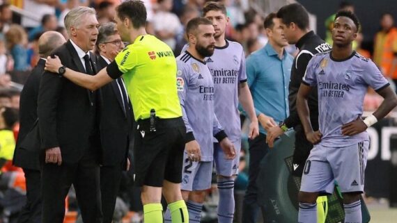 Vini Jr. ao lado de outros jogadores do Real e de Ancelotti, que reclama com o árbitro. (foto: Jose Jordan/AFP)