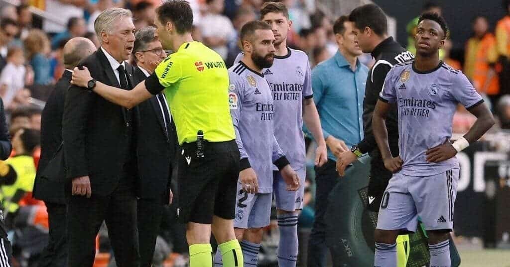 Vini Jr. ao lado de outros jogadores do Real e de Ancelotti, que reclama com o árbitro. (foto: Jose Jordan/AFP)