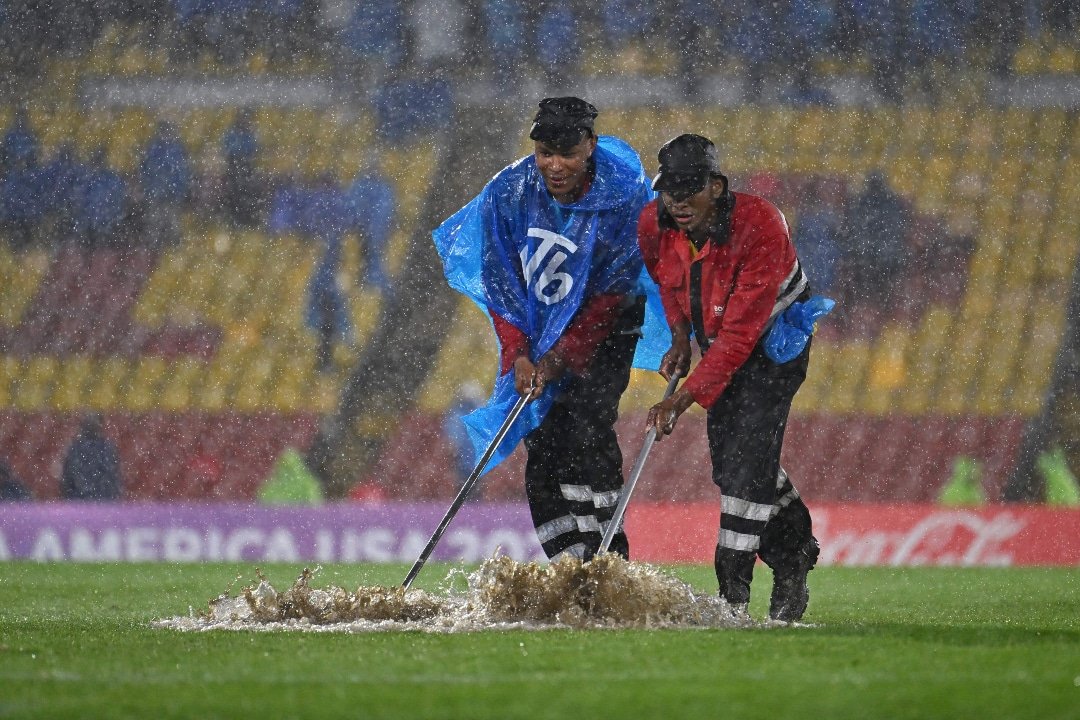 Funcionários usam rodo para tirar excesso de água do gramado. (foto: JUAN BARRETO)