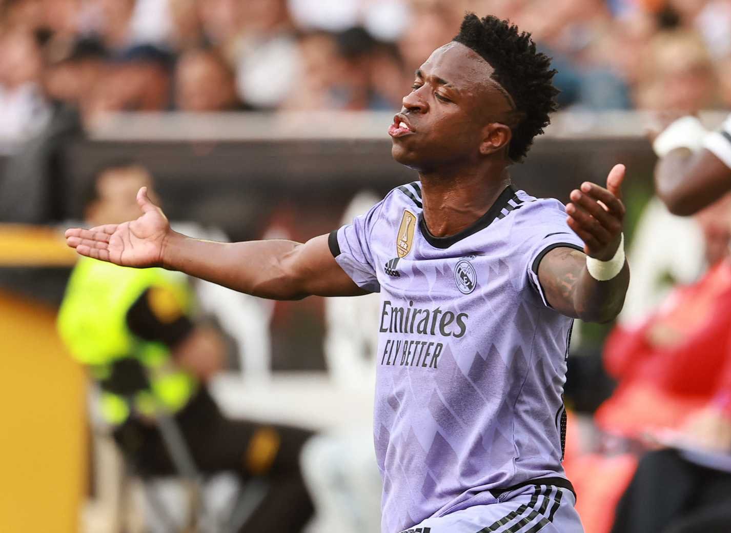 Jogador do Real Madrid, Vinicius Júnior aparece com os braços abertos e com olho fechado (foto: José Jordan/AFP)