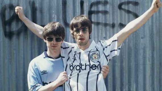 Foto de arquivo de Lian e Noel Gallagher, vestidos com a camisa do Manchester City, se abraçam (foto: Reprodução)