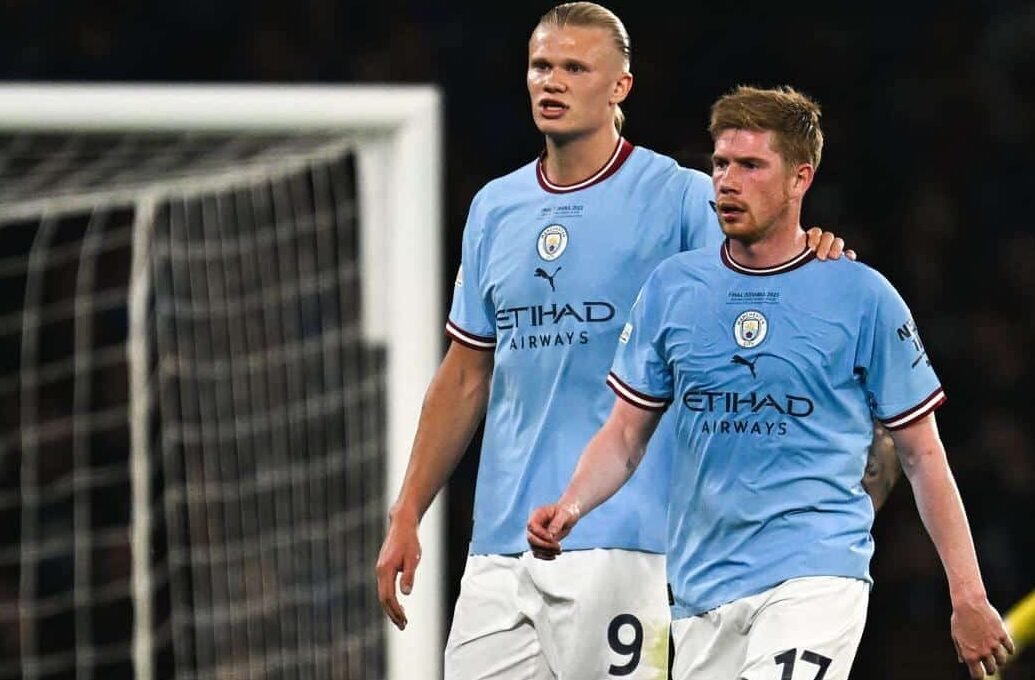 Haaland e De Bruyne abraçados em campo (foto: Paul ELLIS / AFP)