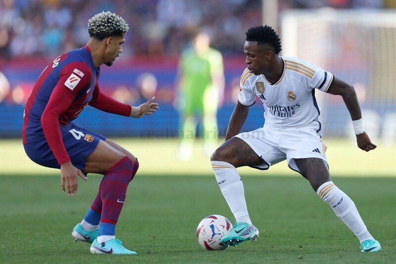 Vini Jr em disputa de bola com Ronald Araujo, defensor do Barcelona (foto: Antonio Villalba / Realmadrid.com)