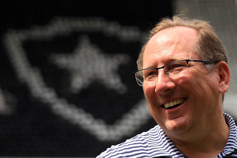 John Textor sorri em frente ao escudo do Botafogo (foto: Vitor Silva/Botafogo)