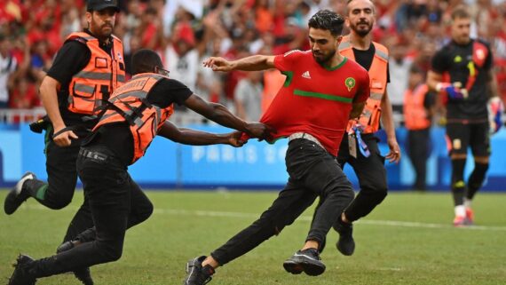 Homem é perseguido por seguranças ao invadir campo de futebol (foto: Sylvain THOMAS / AFP)