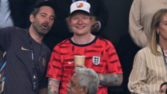 Ed Sheeran, de camisa vermelha, em jogo na Inglaterra (foto: INA FASSBENDER / AFP)