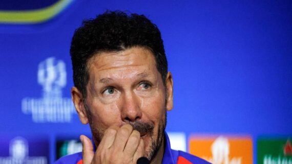 Simeone coça a boca durante coletivo à frente de fundo azul (foto: Oscar del Pozo/AFP)