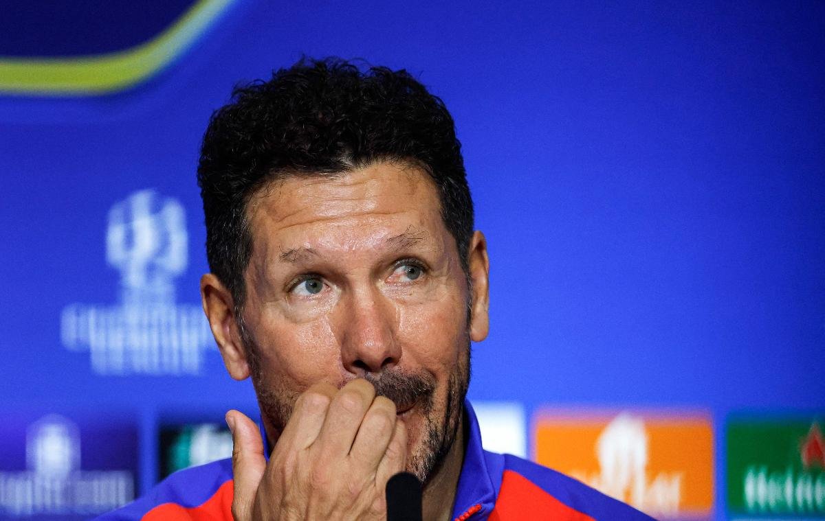 Simeone coça a boca durante coletivo à frente de fundo azul (foto: Oscar del Pozo/AFP)