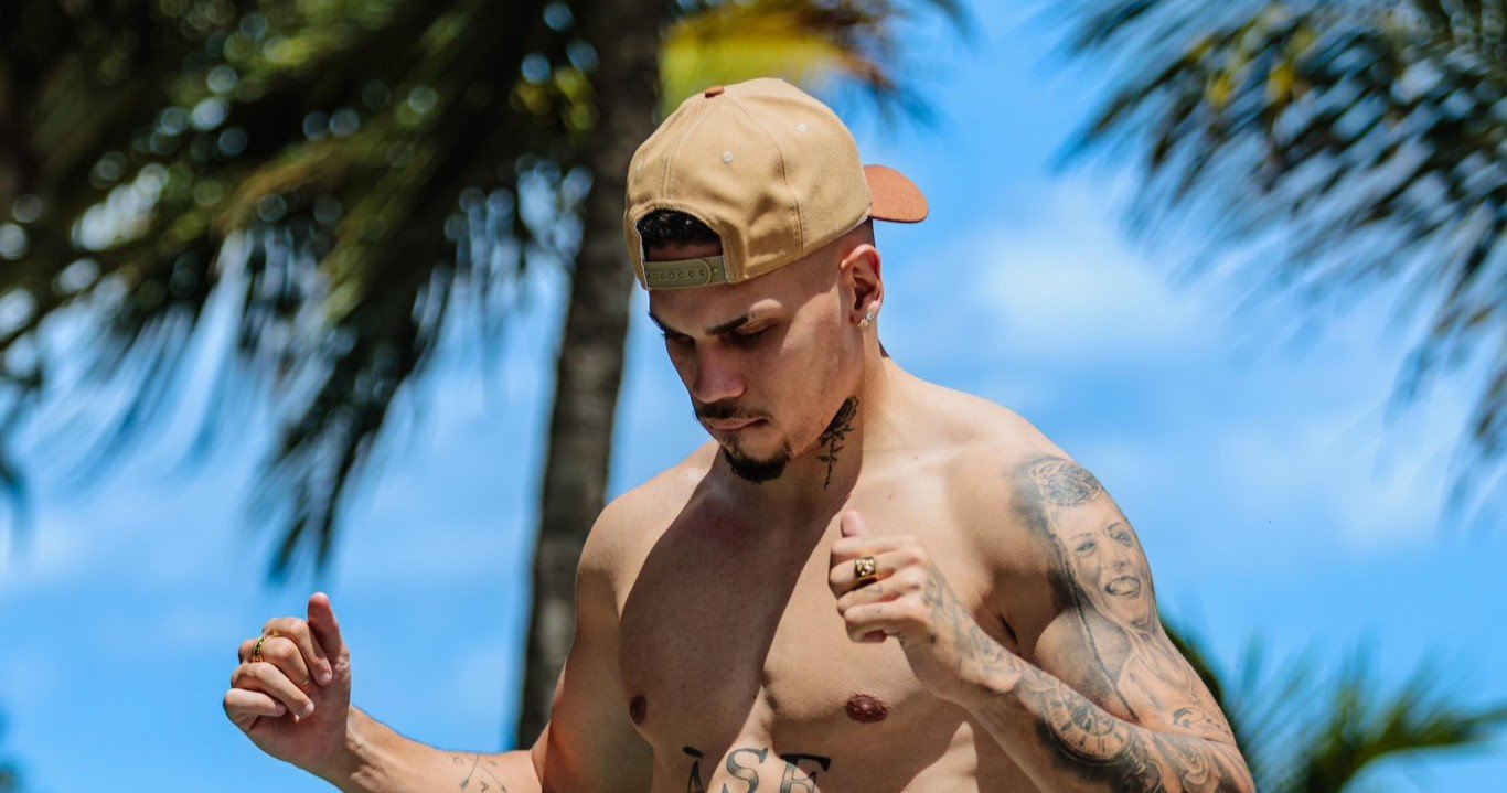 Paulinho, sem camisa e usando boné. Ao fundo, céu azul e palmeiras (foto: Reprodução)