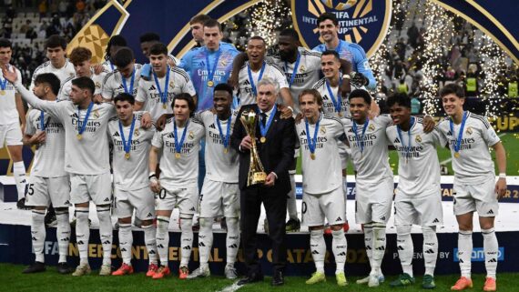 Rodeado dos jogadores do Real Madrid, Ancelotti posa com troféu do Intercontinental (foto: MAHMUD HAMS/AFP)