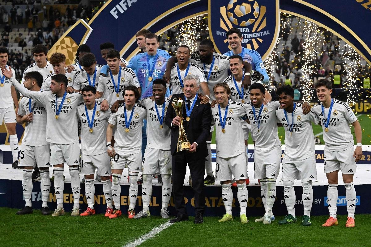 Rodeado dos jogadores do Real Madrid, Ancelotti posa com troféu do Intercontinental (foto: MAHMUD HAMS/AFP)