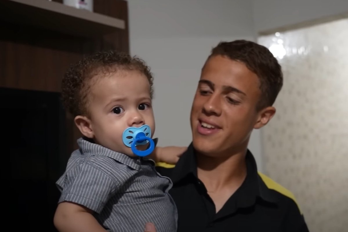 Jogador da Copinha, Murilo Lélis carrega o filho no colo (foto: Reprodução / Cartoloucos)