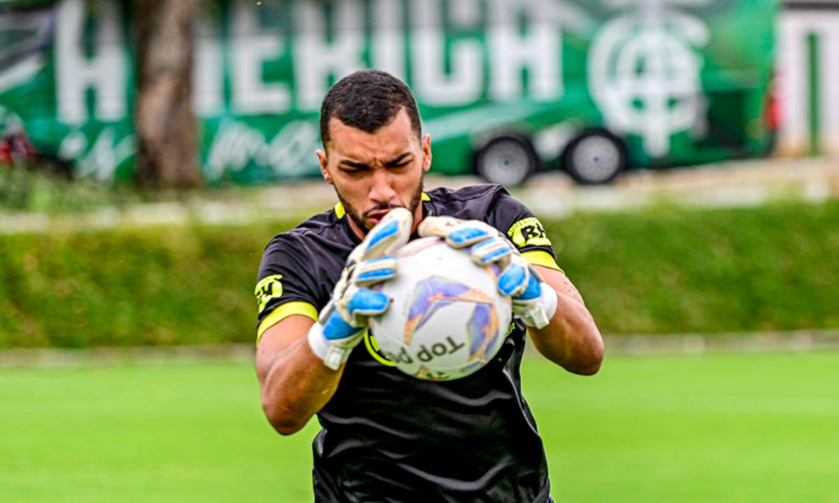 Dalberson segura a bola de futebol com as duas mãos (foto: Mourão Panda/América)