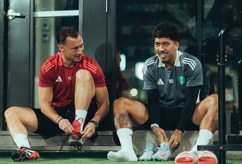 Firmino sentado calçando chuteiras (foto: Divulgação/Al-Ahli)