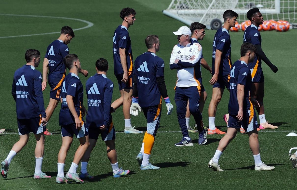 Ancelotti entre jogadores do Real Madrid no campo de treinamento (foto: Thomas Coex/AFP)