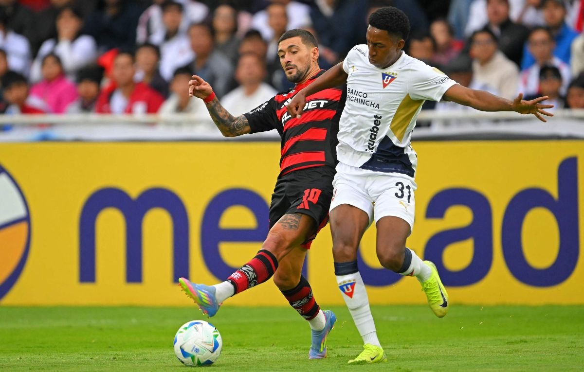 Arrascaeta, do Flamengo, e Daniel de La Cruz, da LDU (foto: Rodrigo BUENDIA / AFP)