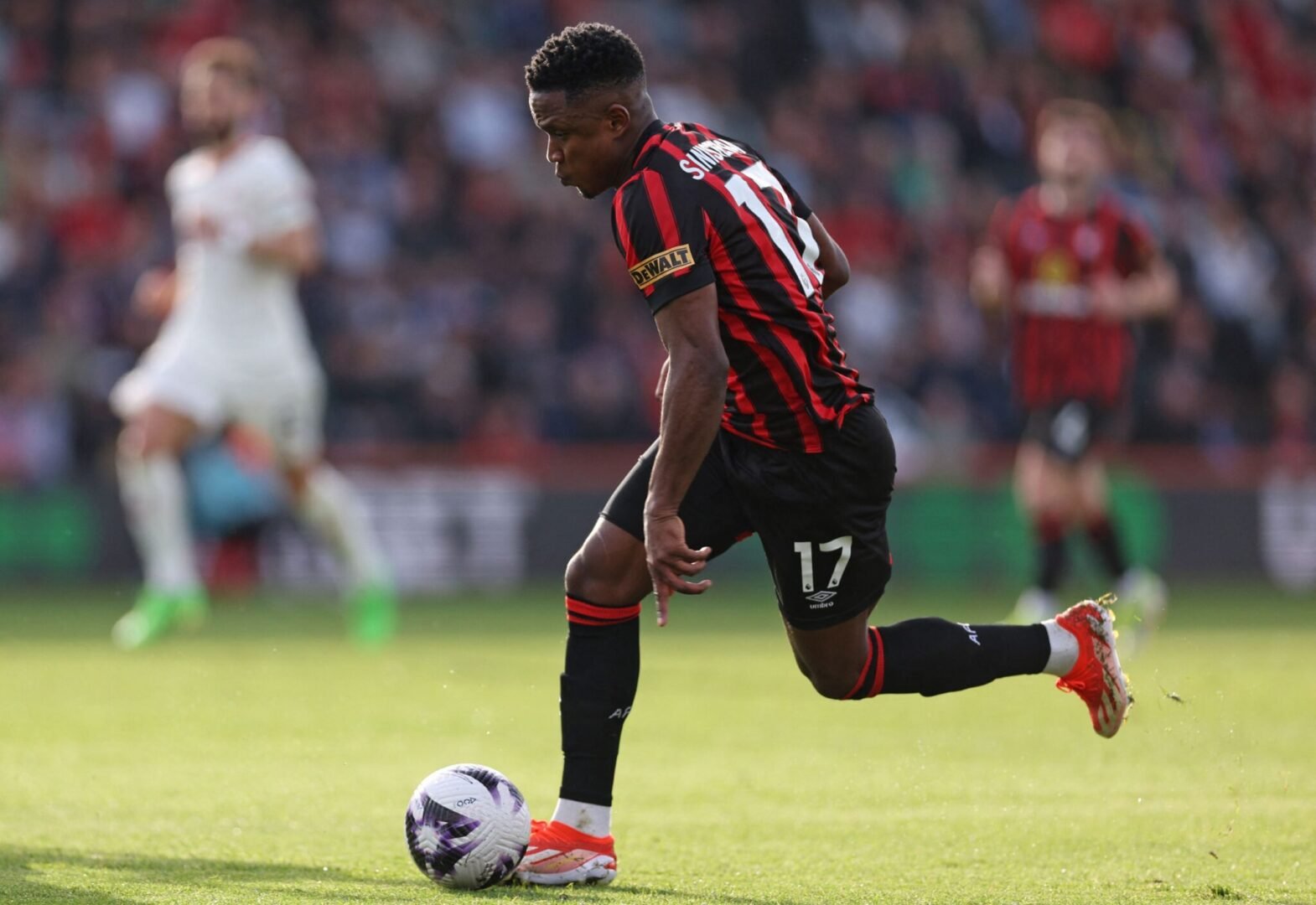 Jogador corre pelo campo com camisa de manga curta com listras vermelhas e pretas (foto: Adrian Dennis/AFP)