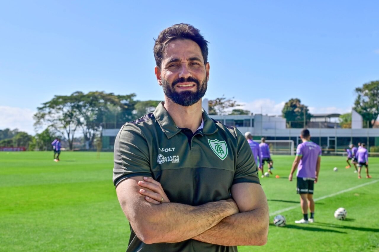 Paulo Assis vestido com a camisa do América e de braços cruzados (foto: Mourão Panda/América)
