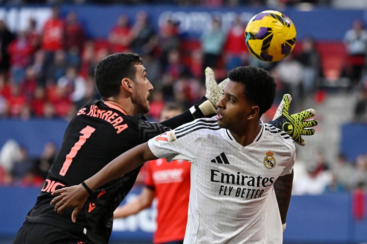 Goleiro do Osasuna se prepara para pegar bola, e jogador do Real Madrid está próximo ao goleiro (foto: Ander Gillenea/AFP)