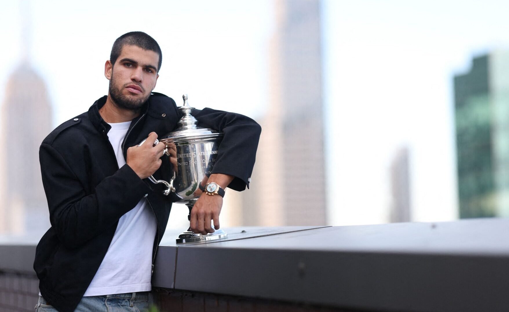 Carlos Alcaraz abraça troféu do US Open com prédios de Nova Iorque ao fundo (foto: Clive Brunskill/AFP)