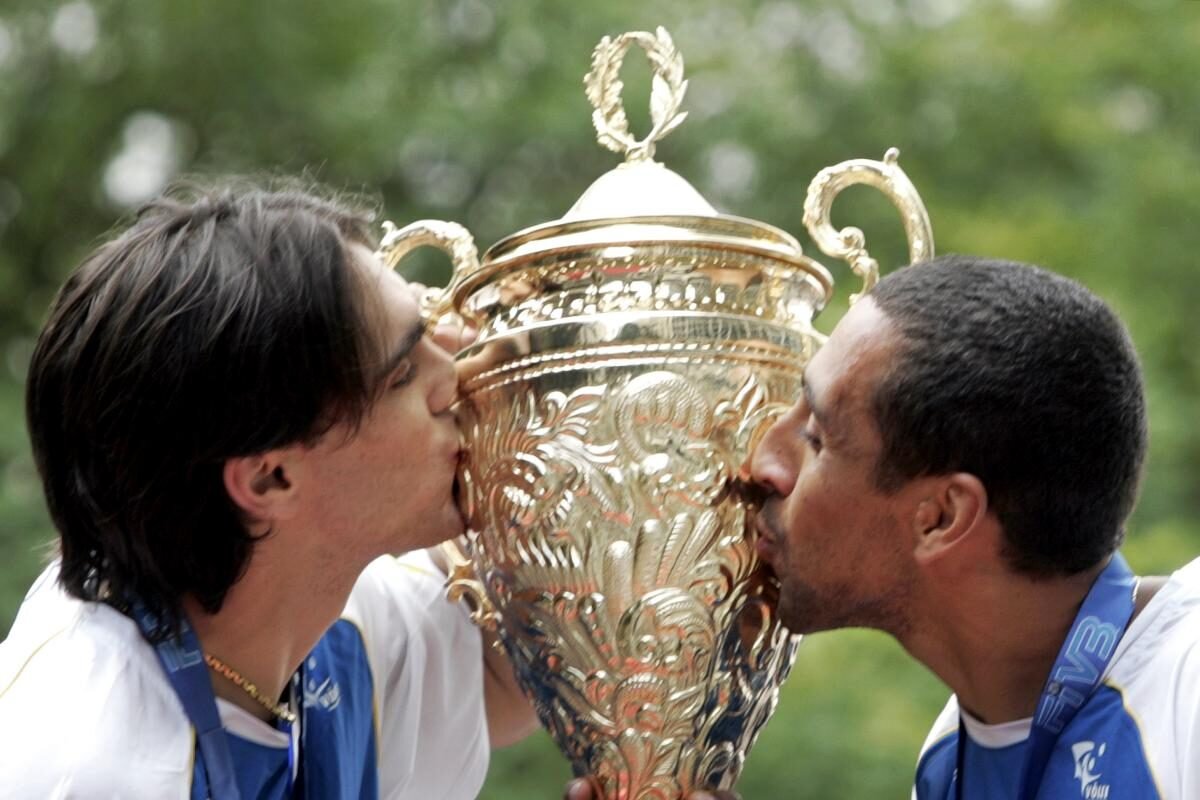 Giba e Serginho, lendas do vôlei brasileiro, beijam taça do Mundial em 2006 (foto: PAULO WHITAKER/AFP)