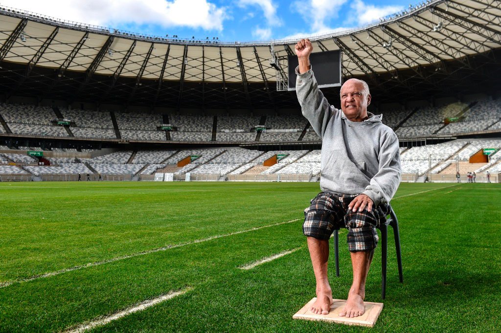 Reinaldo com o braço direito erguido e marcando os pés para a calçada da fama do Mineirão