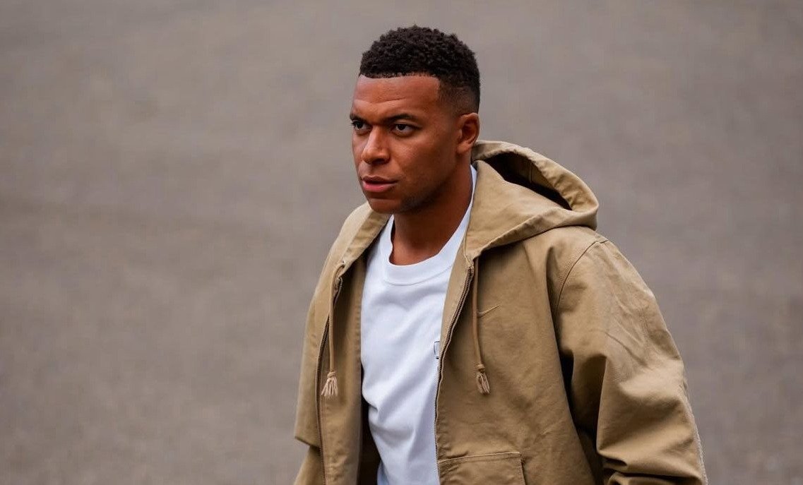 Mbappé vestido de jaqueta marrom e blusa branca (foto: Divulgação/Mbappé)