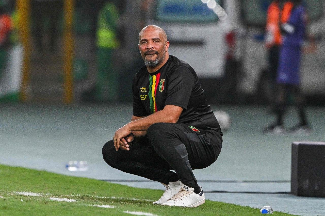 Eric Chelle, técnico da Nigéria, de camisa e calças pretas e agachado na beira do campo (foto: Issouf Sanogo/ AFP)