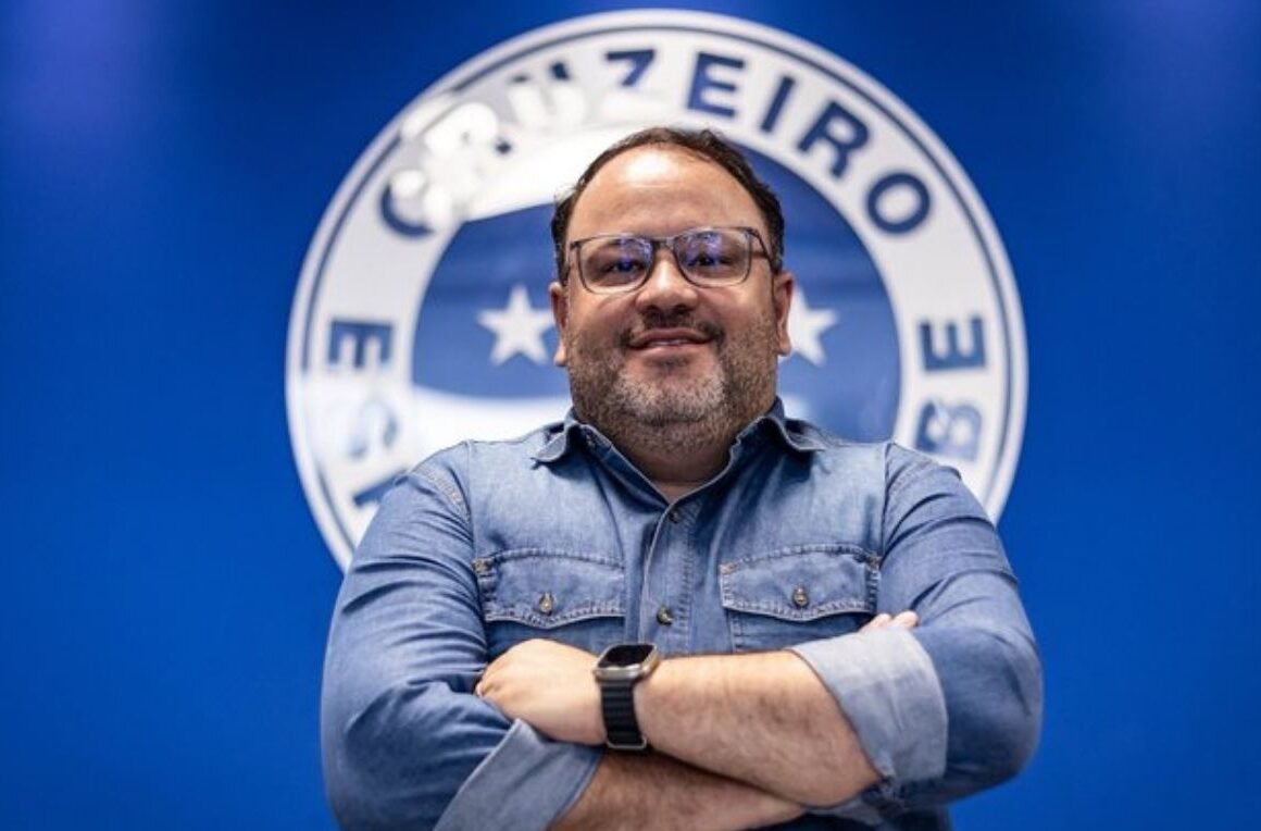 Fred Cascardo vestido de camisa azul e à frente do escudo do Cruzeiro (foto: Cruzeiro/Divulgação)