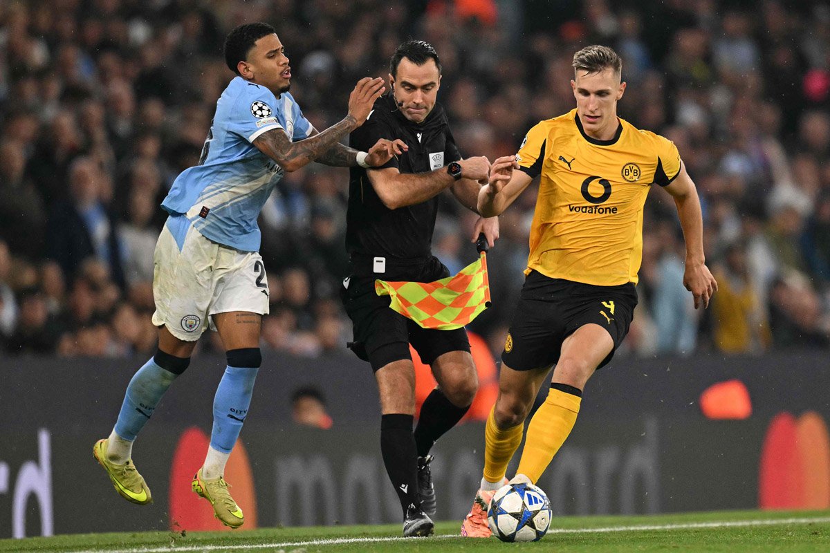 Savinho, do City, tromba no bandeira em disputa de bola com Schlotterbeck, do Dortmund (foto: Oli SCARFF / AFP)