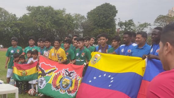Atletas que participaram da Copa dos Refugiados e Imigrantes de 2022, em BH, posando para foto com suas bandeiras nas mãos 