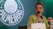 Leila Pereira falando ao microfone, de camisa verde e à frente do escudo do Palmeiras (foto: César Greco/Palmeiras)