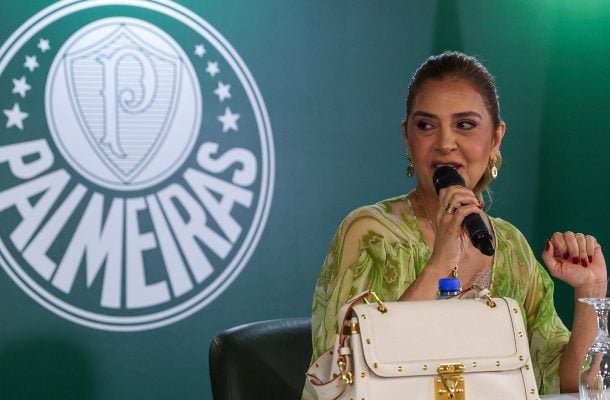 Leila Pereira falando ao microfone, de camisa verde e à frente do escudo do Palmeiras (foto: César Greco/Palmeiras)
