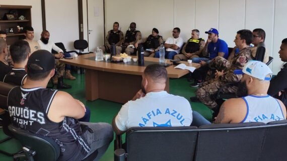 Membros da Polícia Militar de Minas Gerais e integrantes de torcidas organizadas de Cruzeiro e Corinthians sentados em cadeiras em torno de uma mesa de madeira (foto: PMMG/Divulgação)
