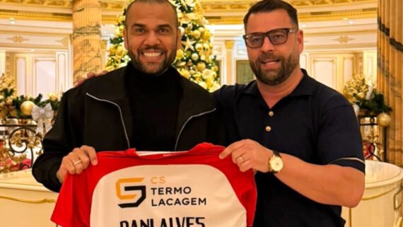 Daniel Alves segurando uma camisa de futebol com seu nome ao lado de homem (foto: Divulgação/São João de Ver)