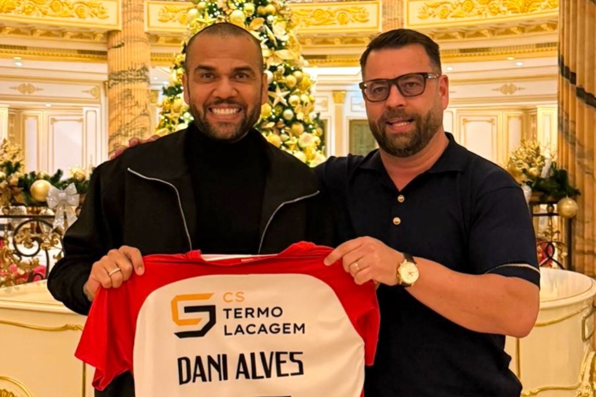 Daniel Alves segurando uma camisa de futebol com seu nome ao lado de homem (foto: Divulgação/São João de Ver)