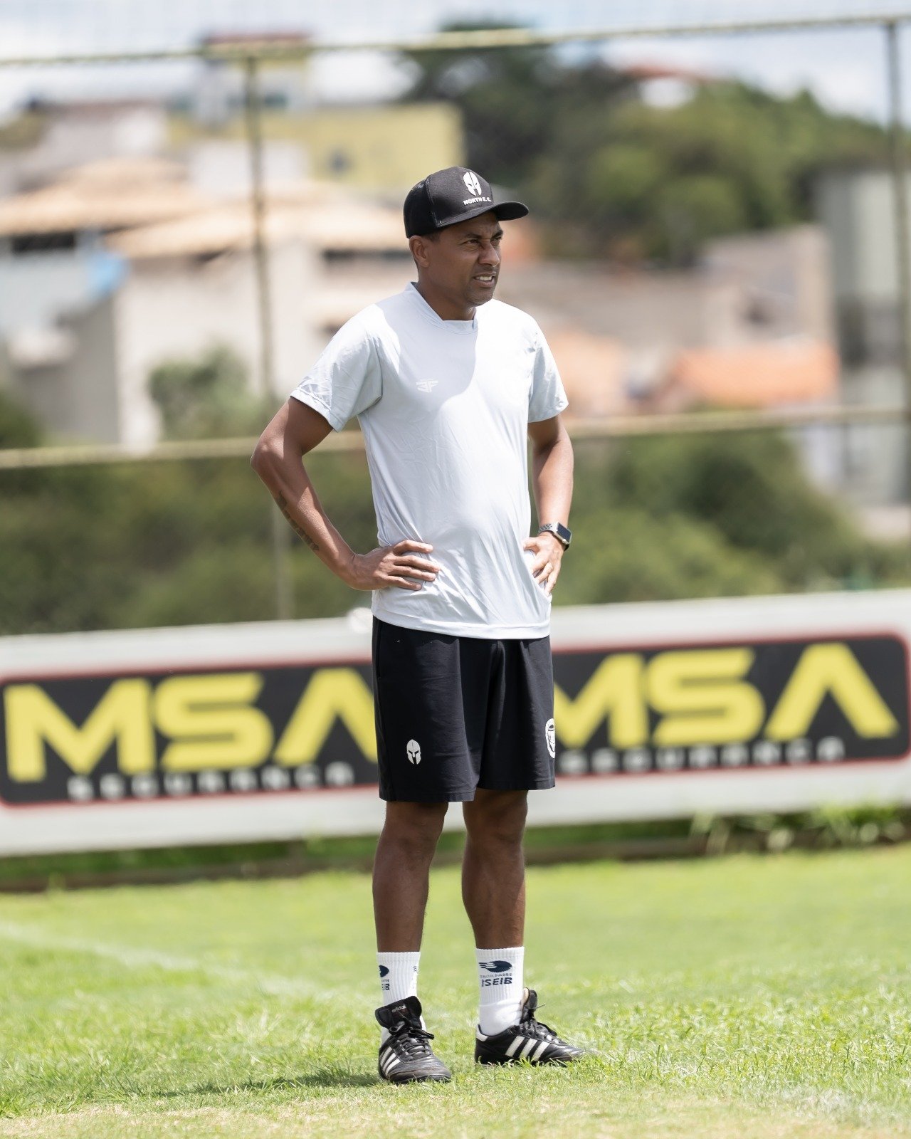 Técnico do North, Kleberson de camisa branca, short e boné pretos e as mãos na cintura - (foto: Lara Mendes/Divulgação)