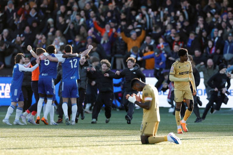 Jogadores do Macclesfield, de azul, comemoram a vitória inesperada sobre o Crystal Palace pela Copa da Inglaterra, neste sábado (10) (foto: Jason Cairnduff/Action Images/Reuters)